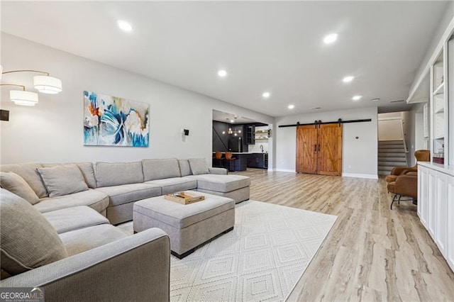 living area featuring light wood-style flooring, recessed lighting, and a barn door