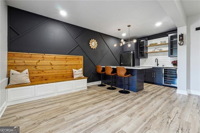 bar with indoor wet bar, baseboards, black refrigerator, and wine cooler