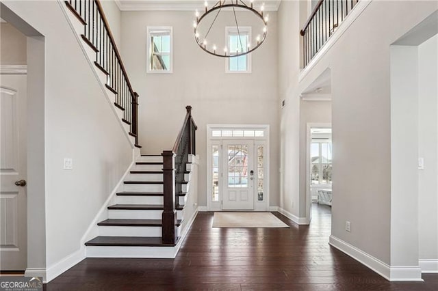 entryway featuring stairway, a high ceiling, baseboards, a chandelier, and hardwood / wood-style flooring