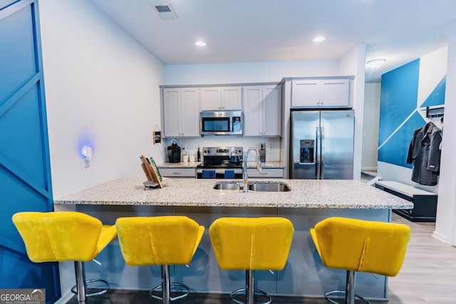 3132 Meadowstone Ln SW, Atlanta, GA 30331 - kitchen with appliances with stainless steel finishes, a breakfast bar, light stone countertops, light wood-style flooring, and recessed lighting
