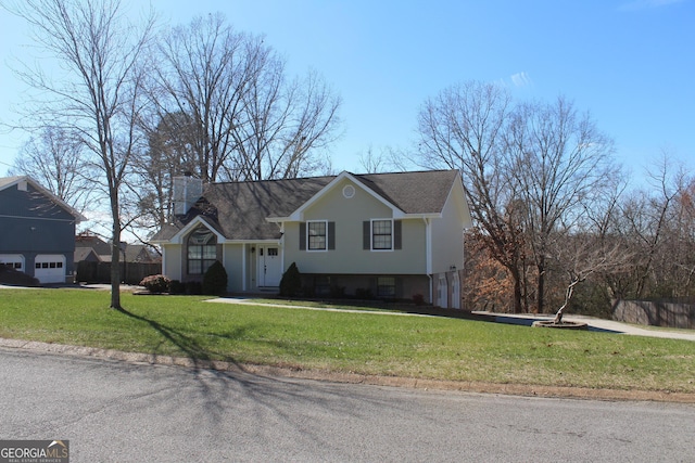 view of front of home with a chimney, a garage, a front lawn, and fence