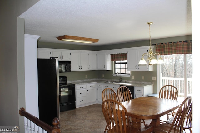 kitchen featuring white cabinetry, light countertops, black appliances, and a chandelier