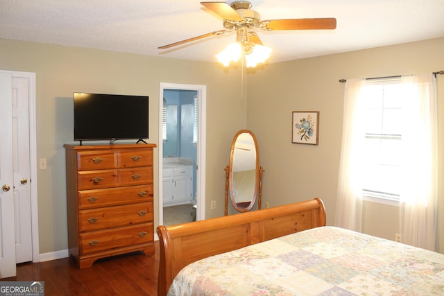 bedroom featuring dark wood-type flooring, connected bathroom, baseboards, and ceiling fan