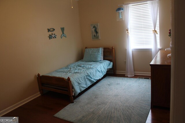bedroom featuring visible vents, baseboards, and wood finished floors