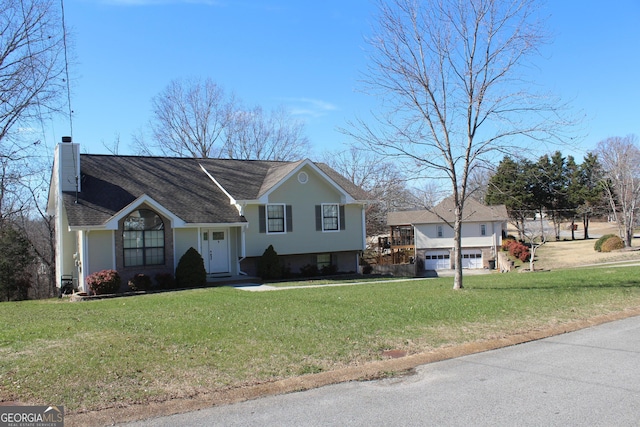 split level home with a chimney, a front lawn, and roof with shingles
