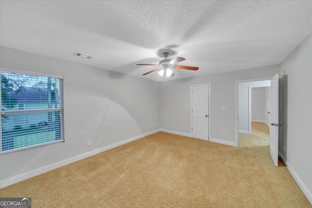 empty room with a ceiling fan, baseboards, light colored carpet, and visible vents