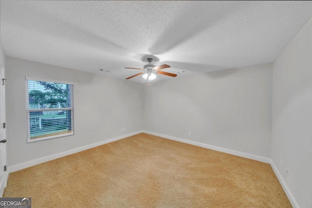 empty room with a ceiling fan, a textured ceiling, baseboards, light colored carpet, and visible vents