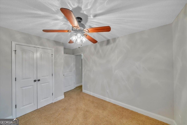 unfurnished bedroom featuring a closet, baseboards, light colored carpet, and a textured ceiling