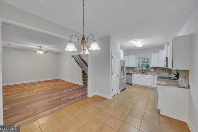 kitchen featuring a sink, white cabinets, tasteful backsplash, appliances with stainless steel finishes, and decorative light fixtures