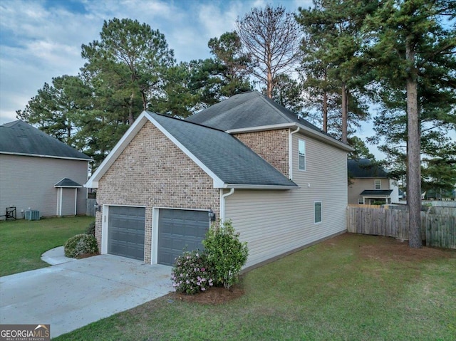 view of property exterior with concrete driveway, roof with shingles, fence, a garage, and a lawn