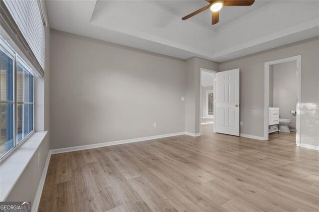 4625 Thermal Ct, Douglasville, GA 30135 - unfurnished bedroom with connected bathroom, baseboards, light wood-style flooring, and a raised ceiling
