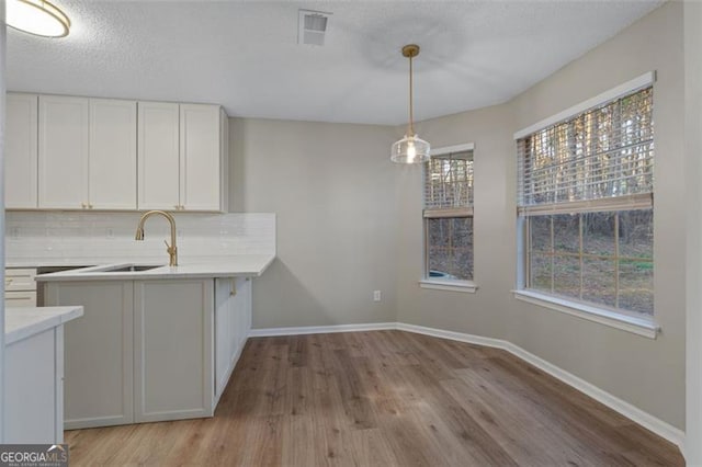 4625 Thermal Ct, Douglasville, GA 30135 - kitchen with decorative backsplash, light wood-style floors, light countertops, white cabinets, and a sink