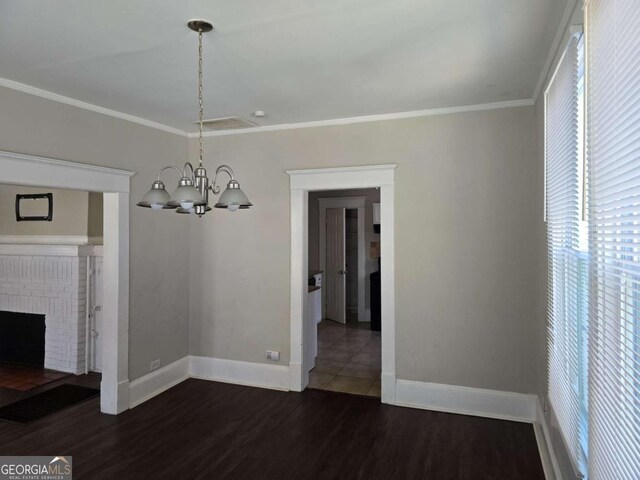unfurnished dining area with baseboards, ornamental molding, a chandelier, and dark wood finished floors