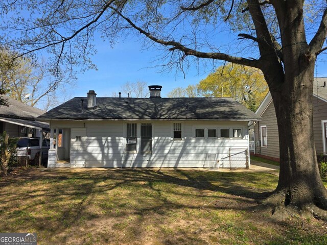 back of house featuring a yard and a chimney