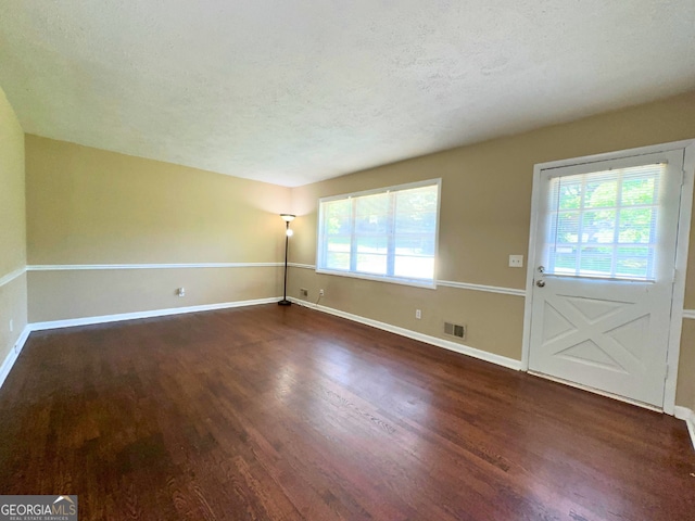 unfurnished room with wood finished floors, healthy amount of natural light, baseboards, and a textured ceiling