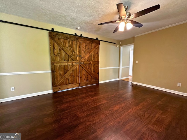 unfurnished bedroom featuring a textured ceiling, baseboards, wood finished floors, a barn door, and ceiling fan