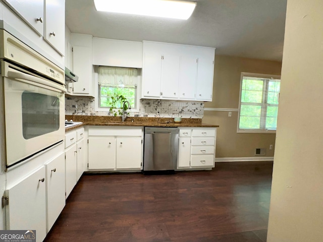 kitchen with white appliances, a sink, backsplash, dark countertops, and under cabinet range hood