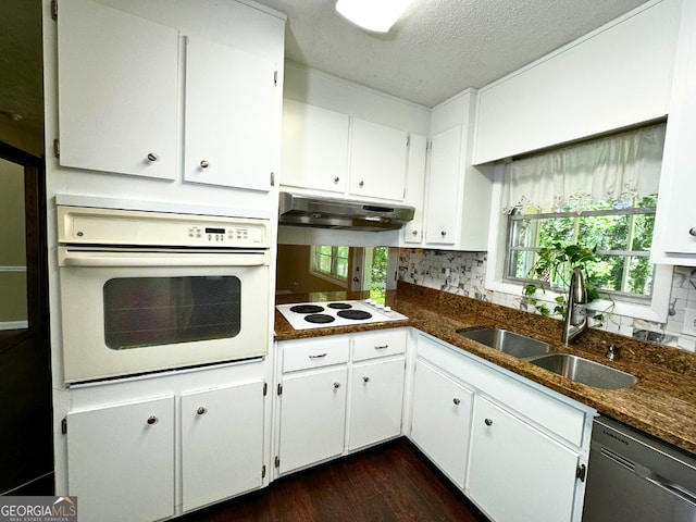 kitchen with white appliances, under cabinet range hood, decorative backsplash, a sink, and a textured ceiling