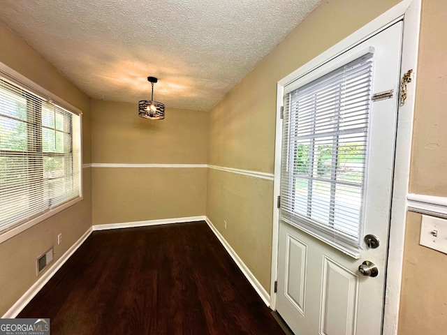 unfurnished dining area featuring wood finished floors, a textured ceiling, and baseboards