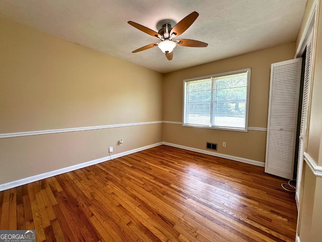 unfurnished bedroom featuring wood finished floors, baseboards, a closet, a textured ceiling, and a ceiling fan