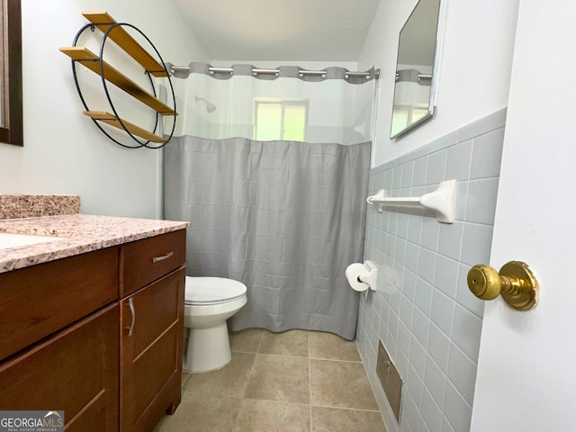 bathroom with tile walls, vanity, toilet, tile patterned floors, and a shower with curtain