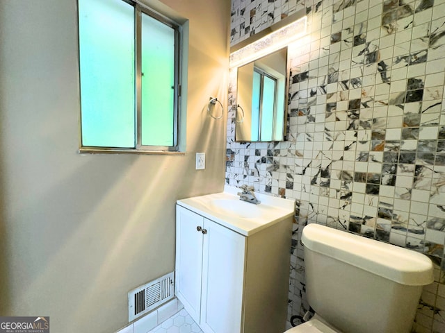 half bathroom with vanity, toilet, and tasteful backsplash