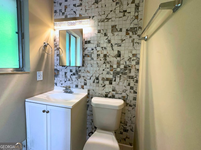 bathroom featuring toilet, vanity, tile walls, and decorative backsplash