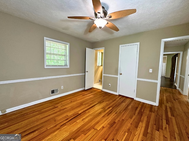 unfurnished bedroom with wood finished floors, baseboards, a textured ceiling, and ceiling fan