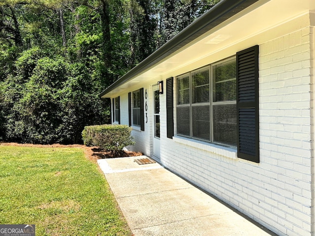 view of side of home featuring brick siding and a yard
