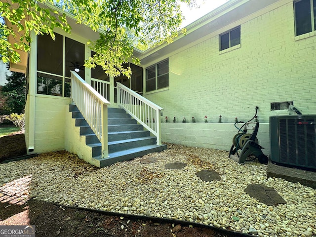 view of side of property with central AC unit, brick siding, and crawl space