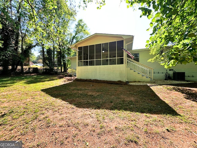 view of green lawn with a sunroom and central air condition unit
