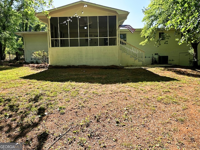 back of house featuring a sunroom and a lawn