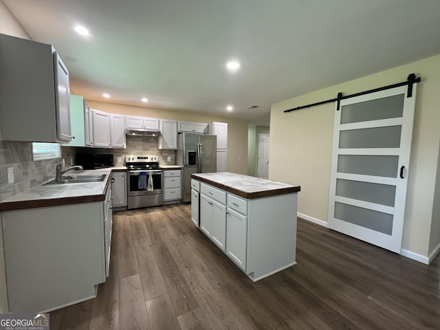 411 Woodland Dr, Hinesville, GA 31313 - kitchen with dark wood finished floors, a barn door, a center island, stainless steel appliances, and decorative backsplash