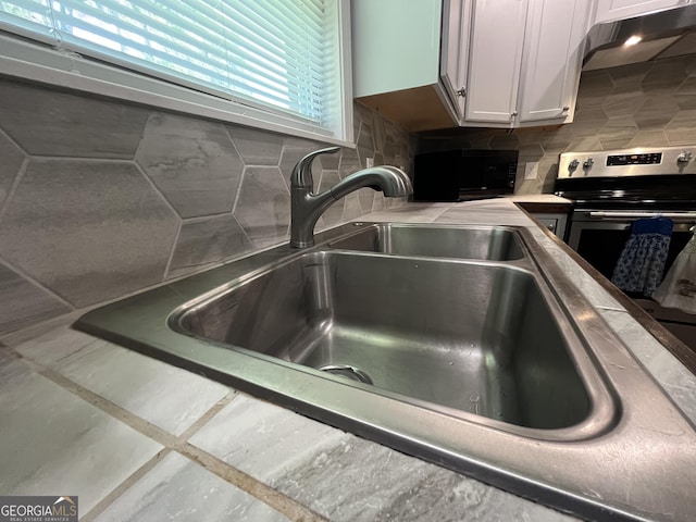 411 Woodland Dr, Hinesville, GA 31313 - details with stainless steel electric stove, black microwave, tasteful backsplash, white cabinets, and under cabinet range hood