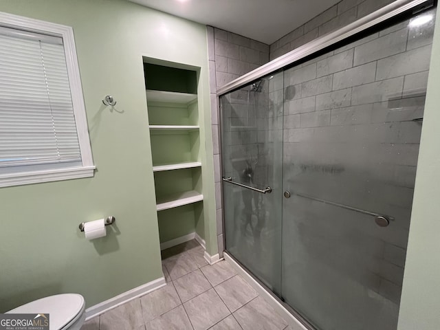411 Woodland Dr, Hinesville, GA 31313 - bathroom featuring built in features, toilet, a stall shower, baseboards, and tile patterned floors