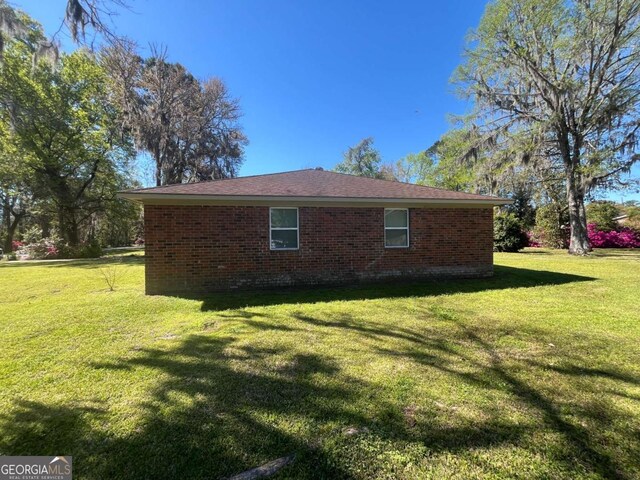 411 Woodland Dr, Hinesville, GA 31313 - view of home's exterior with brick siding and a yard