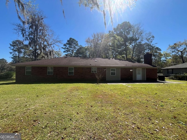 411 Woodland Dr, Hinesville, GA 31313 - back of house with a patio area, brick siding, a chimney, and a lawn