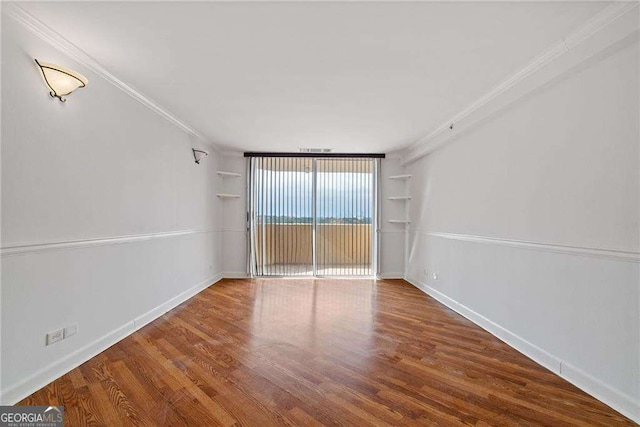 spare room featuring ornamental molding, built in features, baseboards, and wood finished floors