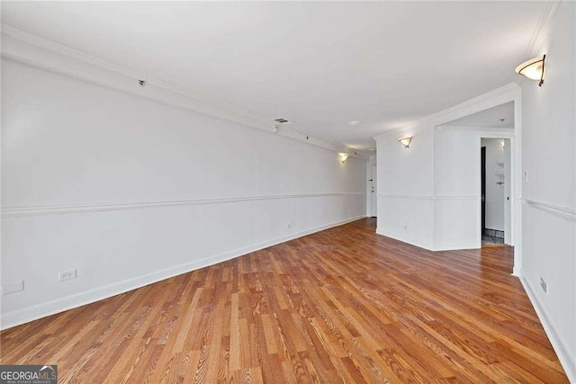 empty room featuring light wood finished floors, baseboards, and ornamental molding