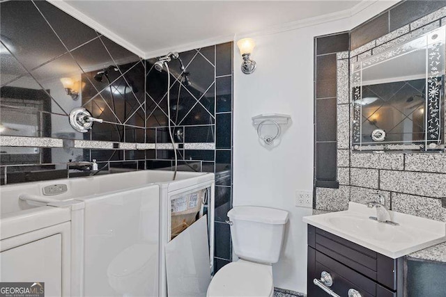 bathroom featuring decorative backsplash, independent washer and dryer, ornamental molding, toilet, and vanity
