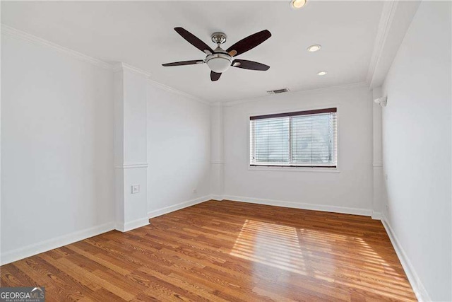 spare room with crown molding, light wood-type flooring, baseboards, visible vents, and ceiling fan