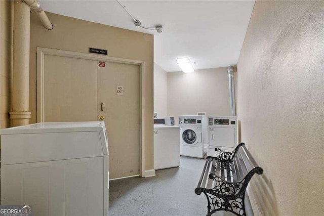 community laundry room with a textured wall and separate washer and dryer