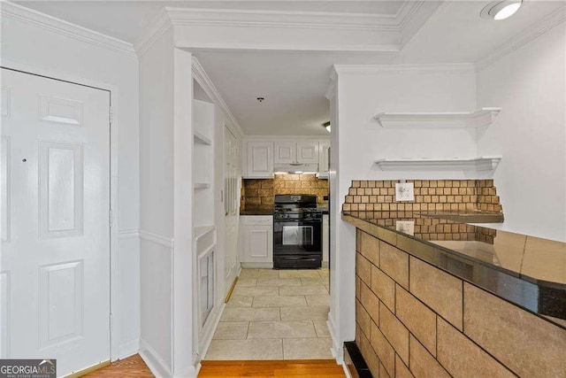 kitchen with white cabinets, ornamental molding, dark countertops, gas stove, and backsplash