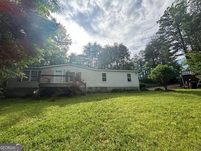 rear view of property with a wooden deck and a yard