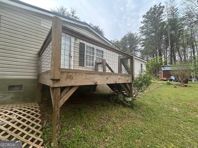 view of home's exterior with a wooden deck, a yard, and crawl space