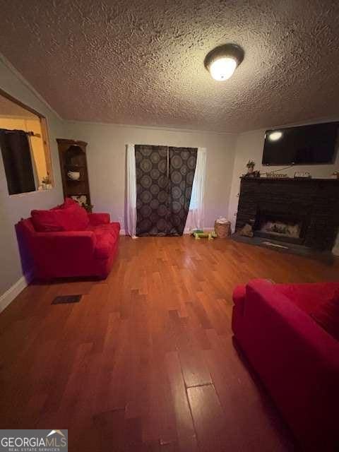 living room featuring a textured ceiling, wood finished floors, and a fireplace