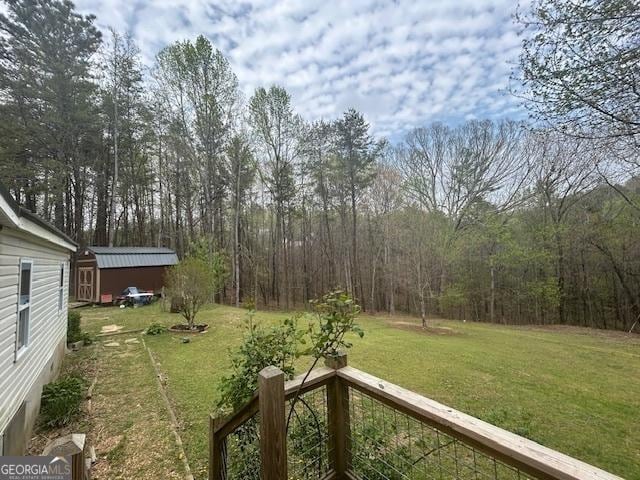 view of yard with an outdoor structure, a shed, and a view of trees