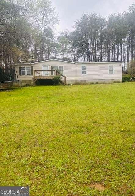 view of yard featuring a trampoline and a wooden deck