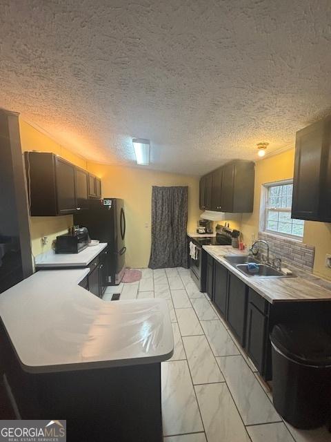 kitchen featuring marble finish floor, a sink, electric range, and light countertops