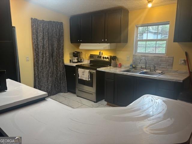 kitchen with decorative backsplash, a sink, light countertops, under cabinet range hood, and electric stove